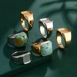 Può includere: Sei anelli sigillo diversi con una montatura di pietra di forma quadrata. Tre anelli sono in oro, due sono in argento e uno ha una pietra turchese.