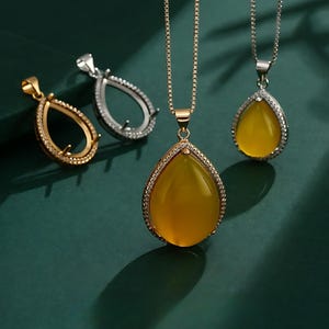 May include: Three silver teardrop-shaped pendant settings with clear cubic zirconia stones. The pendant on the right is on a silver chain and has a yellow stone in the centre.