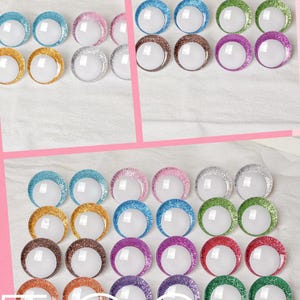 May include: Arrangement of colorful, glitter-rimmed craft embellishments in various colors, including blue, gold, pink, silver, brown, purple, green, and red. The text "With Ur Love" and "FRIDAY" are visible.
