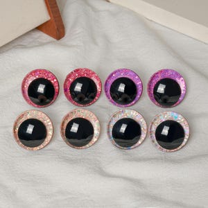 Pu&ograve; includere: Otto grandi occhi rotondi per l'artigianato, con pupille nere e bordi colorati e glitterati. I bordi sono in tonalit&agrave; di rosa, viola e bianco iridescente. Questi occhi di plastica sono ideali per vari progetti fai-da-te.