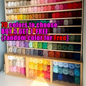 May include: A wooden storage unit filled with balls of yarn in a rainbow of colours. The yarn is organised by shade on numerous shelves. Text on the image reads "70 colours to choose, BUY 5 GET 1 FREE {random colour for Free}".
