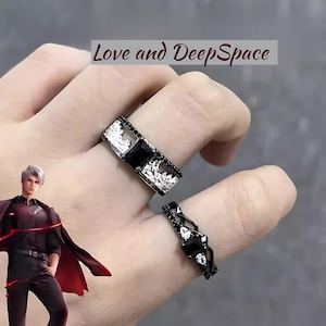 Könnte beinhalten: Zwei schwarze Ringe mit silbernen Akzenten und schwarzen Edelsteinen. Die Ringe werden an einem Finger getragen. Der Text "Love and DeepSpace" ist im Hintergrund sichtbar.