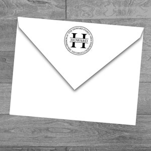 Może przedstawiać: Biała koperta z okrągłą czarną i białą pieczątką. Pieczątka zawiera tekst "The Howard Family" i literę "H" w kółku. Tekst "Howard" znajduje się pod literą "H", a tekst "San Diego, California" znajduje się pod tekstem "Howard".