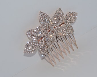 May include: A rose gold hair comb with two sparkling crystal flower designs. The comb has seven teeth.