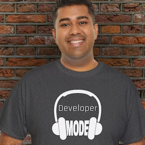 May include: A dark grey t-shirt with a white graphic of headphones and the text "Developer Mode".