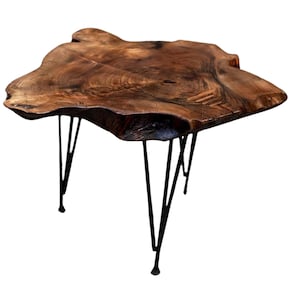 Puede incluir: Una mesa de centro de madera rústica con una tapa de borde vivo y patas de horquilla de metal negro.