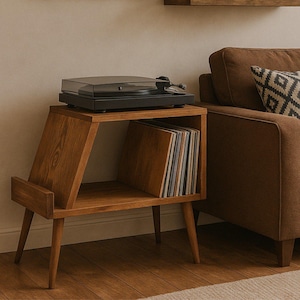 Op de afbeelding: Een houten platenspelerstandaard in mid-century modern stijl. De standaard heeft een plank voor vinylplaten en een zwarte platenspeler. De standaard is ongeveer 61 cm hoog en 46 cm breed.