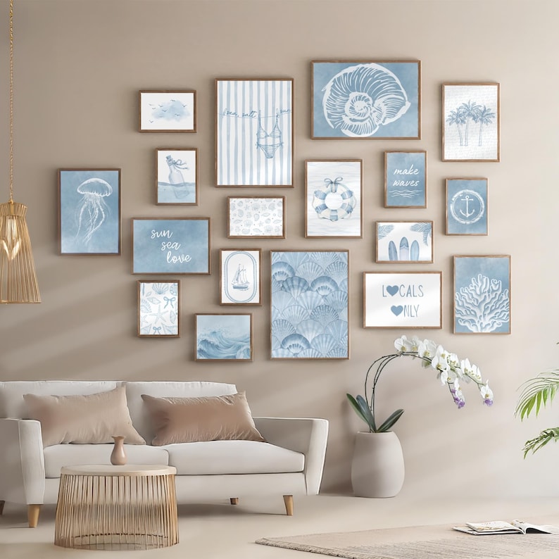 Pode incluir: Uma galeria de impress&otilde;es art&iacute;sticas emolduradas com tema costeiro. As impress&otilde;es apresentam ilustra&ccedil;&otilde;es em aquarela de conchas, elementos n&aacute;uticos e cenas de praia em tons de azul e branco. A arte de parede &eacute; exibida acima de um sof&aacute; branco.