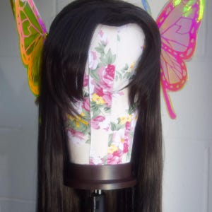 May include: A long black wig with iridescent butterfly hair clips. The butterfly wings are pink and green.