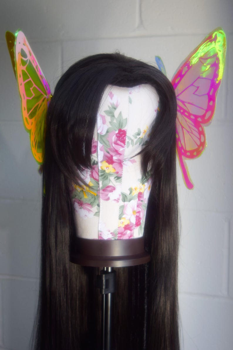 May include: A long black wig with iridescent butterfly hair clips. The butterfly wings are pink and green.