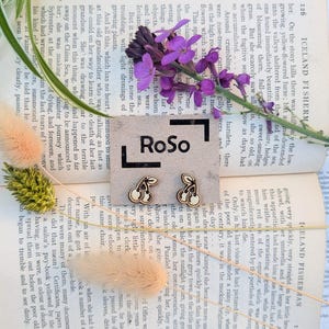 May include: Wooden cherry earrings with a light wood grain finish. The earrings are displayed on a vintage book page with purple flowers and other decorative elements.