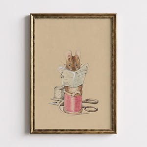 May include: A framed illustration on tan paper featuring a brown mouse wearing glasses and reading a newspaper titled The Tailor and Cutter. The mouse sits atop a large pink thread spool next to a metal thimble and a pair of open sewing scissors.