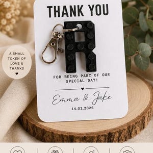 May include: A black letter R keychain with a building block texture attached to a white card. The card reads: THANK YOU, A SMALL TOKEN OF LOVE & THANKS, FOR BEING PART OF OUR SPECIAL DAY!, Emma & Jake, 14.02.2026, THOUGHTFUL • UNIQUE • MEMORABLE.