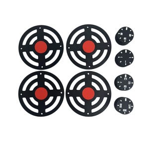 May include: A set of black circular components with a red centre, resembling targets, and smaller black dials with white markings. These components are likely parts of a mechanism or device, possibly for automotive or industrial use.