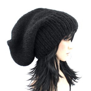 May include: A black slouchy beanie hat made of knit fabric. The hat is large and loose fitting, with a long, flowing design.