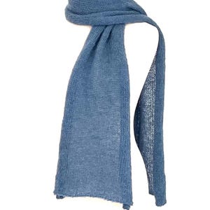 May include: A blue scarf is draped over a wooden form. The scarf is a solid color, with a soft, textured appearance. The scarf is made of a lightweight material, and it appears to be knitted or woven. The scarf is approximately 72 inches long.