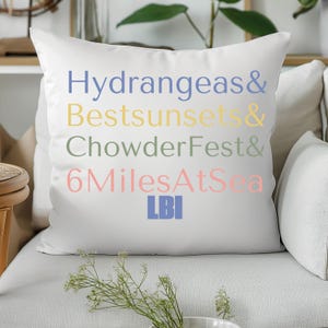 May include: White throw pillow with the text "Hydrangeas & Bestsunsets & ChowderFest & 6MilesAtSea LBI" in different colors.