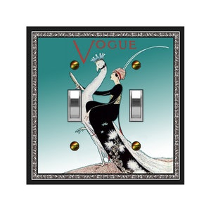 May include: A teal blue light switch cover with a black frame and a silver border. The cover features a vintage illustration of a woman riding a peacock with the word "VOGUE" printed in red letters.