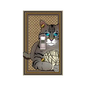May include: A light switch cover featuring a gray tabby cat with blue eyes holding a ball of yarn. The cover has a brown and gold ornate frame with a patterned background.