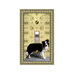 May include: A decorative light switch cover featuring a black and white Border Collie dog. The cover has a gold-colored frame and a patterned background with a light switch in the center. The dog is standing on a gray surface.
