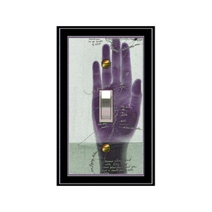 May include: A light switch cover with a purple hand print and a light switch in the center. The hand print has lines and writing on it. The background is a light blue color with writing on it. The text reads "Dreams often start with little whispers and you never know what a small seed will grow into."