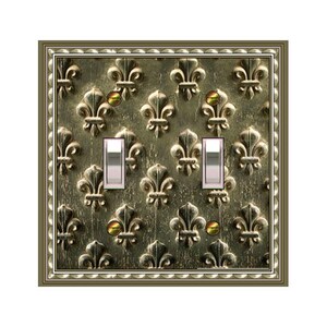 May include: A decorative double light switch cover with a fleur-de-lis pattern in shades of gold and bronze. The cover has a decorative border and two light switches.