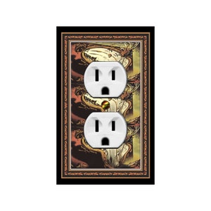 May include: A black framed wall plate with a decorative design featuring a repeating pattern of a stylized image of a deer head. The plate has two white electrical outlets.