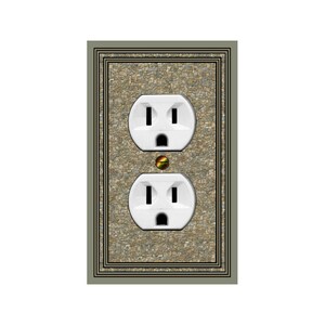 May include: A white electrical outlet with two outlets, set in a stone-patterned wall plate with a decorative frame. The outlet is surrounded by a light brown frame with a darker brown inner border.
