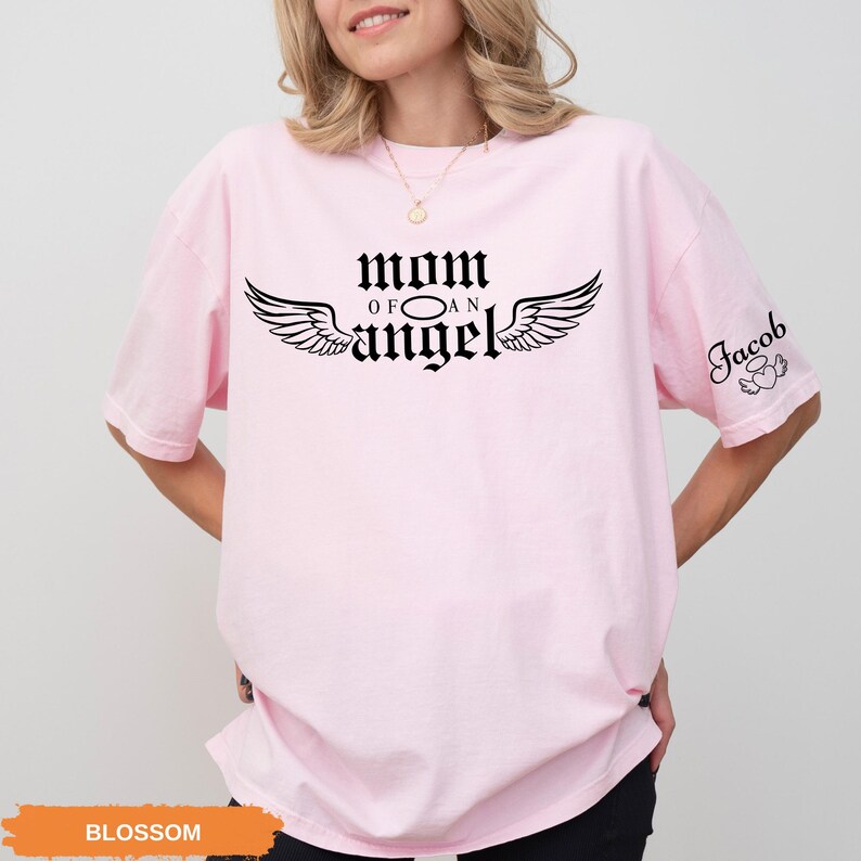 A woman wearing a pink t-shirt with the text "Mom of an angel" printed on it.
