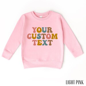 a pink sweatshirt with the words your custom text on it