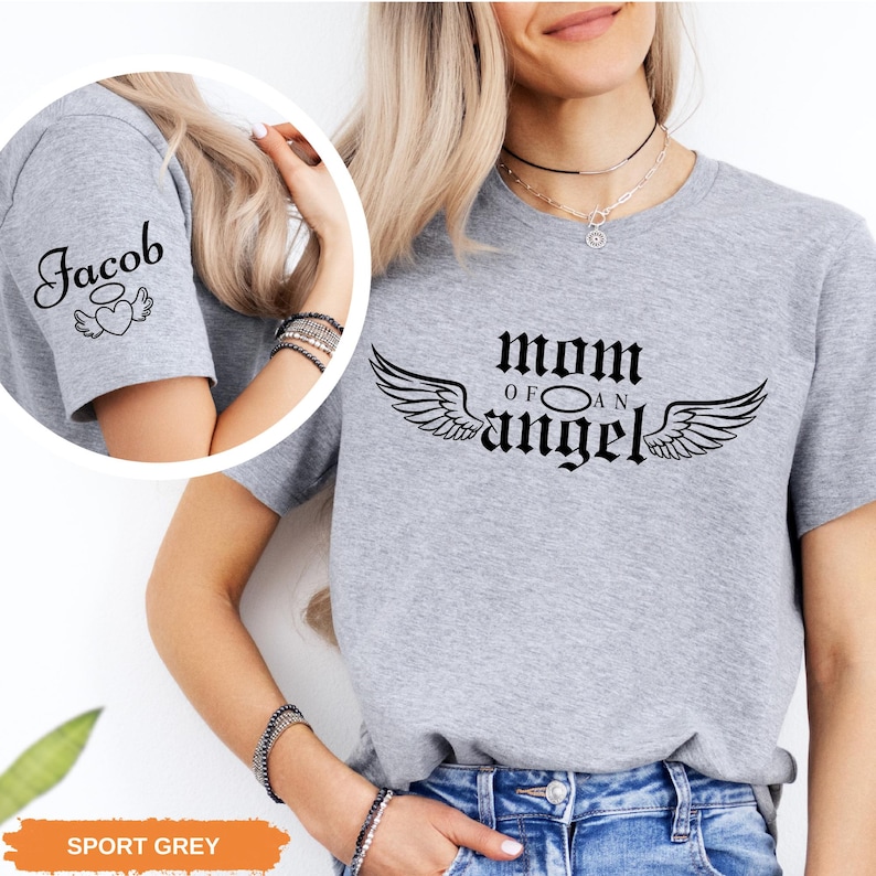 A woman wearing a grey t-shirt with a graphic design and text printed on it.