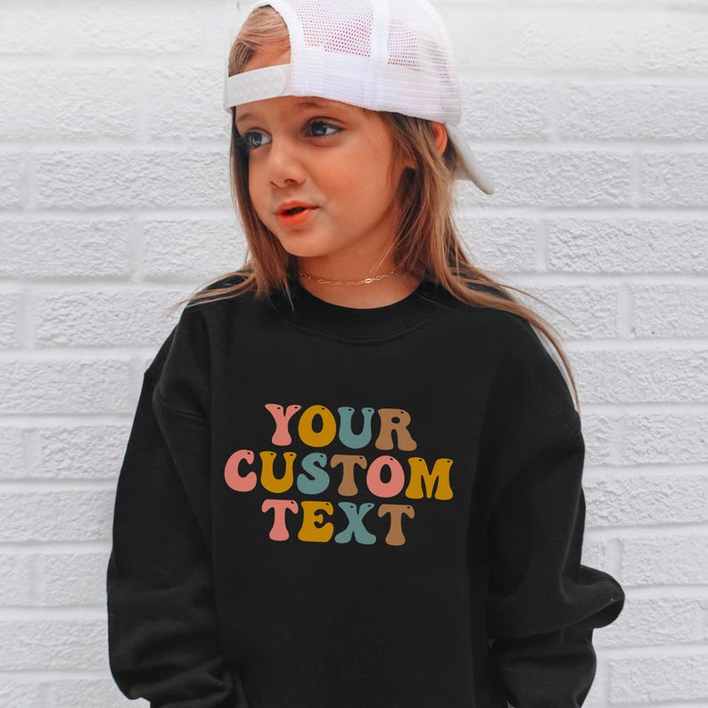 a little girl wearing a black sweatshirt and a white hat