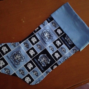 May include: A blue and white Christmas stocking with a Carolina Tar Heels logo and the text "University of North Carolina" repeated on the fabric.