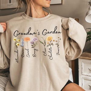 May include: A beige sweatshirt with the text "Grandma's Garden" and floral designs. The names Alexander, Devin, Sarah, Bonny, Oliver, Charlotte, and James are printed below the flowers.