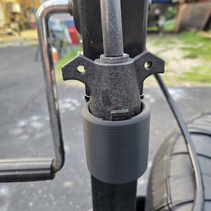 May include: A detailed view of a black trailer hitch assembly. The image shows a cylindrical connector, a mounting bracket with two holes, and a handle. The metal components have a textured finish, indicating robustness.