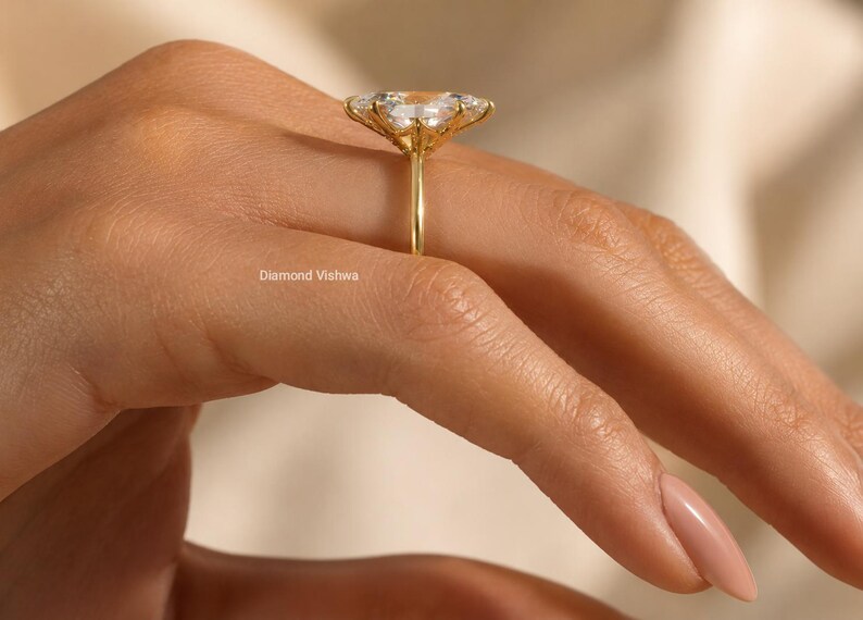 May include: A gold ring with a large, flower-shaped gemstone setting. The ring is on a person's hand, with the focus on the ring's intricate design and the sparkle of the gemstones. The ring is a piece of jewelry.