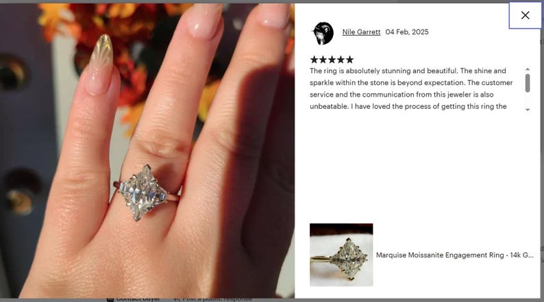 May include: A marquise moissanite engagement ring with a silver band. The ring features a large, sparkling, marquise-cut center stone and smaller side stones. The ring is shown on a person's finger.