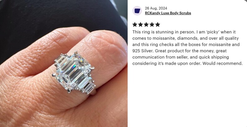 May include: A silver ring with a large, rectangular, emerald-cut center stone and smaller side stones. The ring is set on a finger, showcasing its sparkling facets and elegant design. The ring is made of 925 silver.
