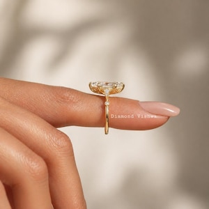 May include: A gold ring with a large, clear, oval-cut gemstone. The ring has a delicate band and intricate detailing around the gemstone. The text "Diamond Vishwa" is visible on the image.