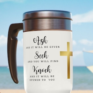 May include: White travel mug with a black handle and a gold cross. The mug has the text "Ask and it will be given, Seek and you will find, Knock and it will be opened to you".