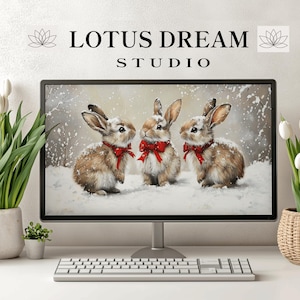 Puede incluir: Un monitor de ordenador muestra una escena invernal con tres conejos con lazos rojos en la nieve. El monitor está sobre un escritorio blanco con un teclado, tulipanes y el texto "LOTUS DREAM STUDIO".