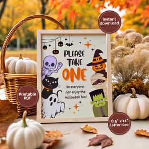 May include: A framed Halloween sign with the text "PLEASE TAKE ONE" and cartoon characters. The sign is 21.6 x 27.9 cm and features a skeleton, black cat, ghost, pumpkin, mummy, and Frankenstein's monster. Pumpkins and autumn leaves surround the sign.