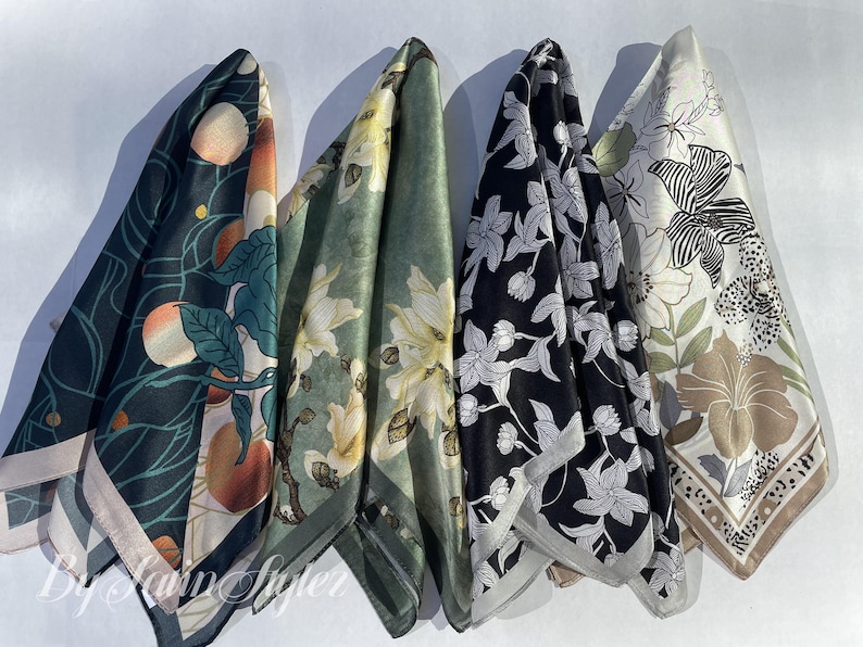 May include: Four silk scarves with floral and botanical designs. The scarves feature a variety of colors, including dark green, black, and cream, with patterns of peaches, flowers, and leaves. Each scarf has a contrasting border.