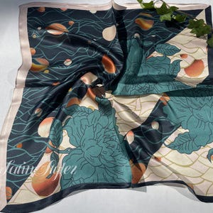 May include: Square silk scarf with a dark teal background, featuring a floral design in teal and cream, with orange and white accents. The scarf has a light pink border and the text "By Latin Riderz" in the bottom left corner.