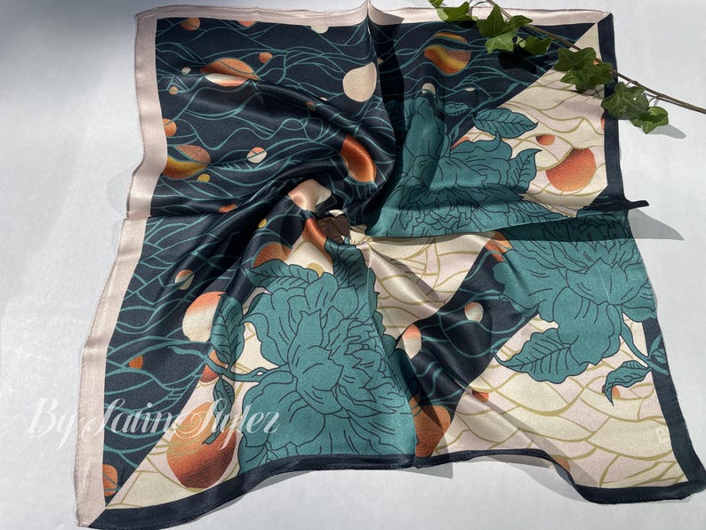 May include: Square silk scarf with a dark teal background, featuring a floral design in teal and cream, with orange and white accents. The scarf has a light pink border and the text "By Latin Riderz" in the bottom left corner.