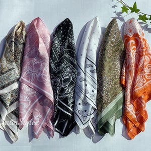 May include: Six different patterned silk scarves in various colours, including pink, black, white, green, and orange. The scarves are arranged in a row, with the ends of each scarf overlapping the next.