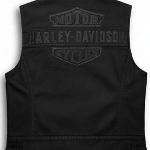 Puede incluir: Chaleco negro sin mangas con el logotipo de Harley-Davidson en relieve en la espalda. El logotipo incluye las palabras "MOTOR HARLEY-DAVIDSON CYCLES" en un diseño de escudo. El chaleco tiene cierre de botón en la cintura y cuello.