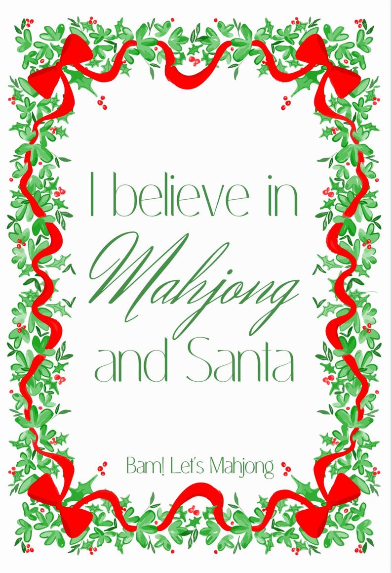 May include: A white rectangular card with a festive Christmas border. The border features green holly leaves, red berries, and red ribbons. The text in the centre reads "I believe in Mahjong and Santa" in green script. At the bottom, it says "Bam! Let's Mahjong".