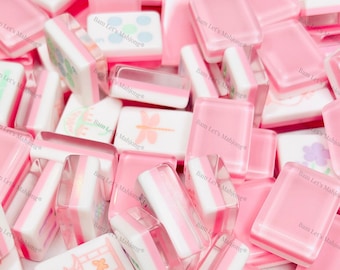 May include: A collection of pink and white Mahjong tiles. Some tiles are solid pink, while others have white and pink stripes or decorative images. The text "JOKER" is visible on one tile. The image has the text "Bam Let's Mahjong".