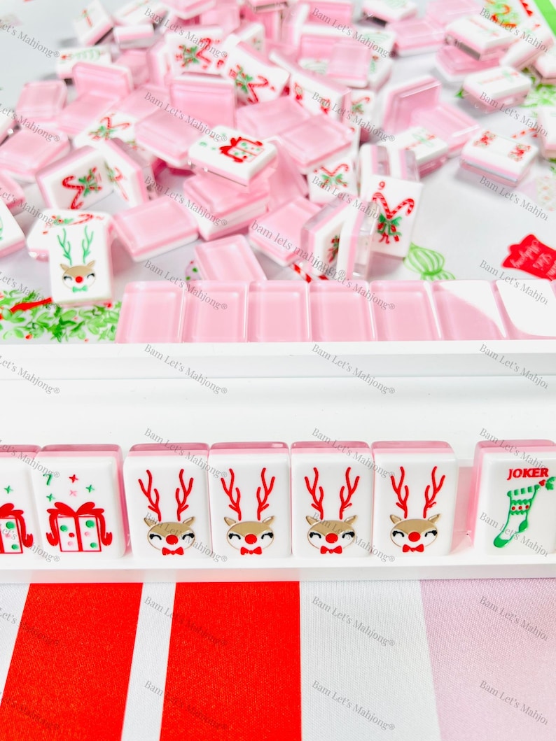 May include: A selection of Christmas-themed Mahjong tiles. The tiles display festive designs such as reindeer, gift boxes, and candy canes. The colour scheme includes white, pink, red, and gold accents, creating a cheerful holiday aesthetic.